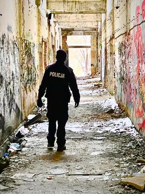 policjant stojący tyłem w pustym budynku