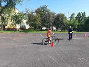 policjant na placu manewrowym wraz z rowerzystą zdającym egzamin na kartę rowerową
