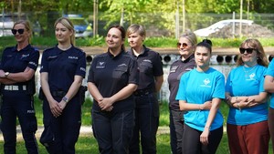 Kobiety w mundurze oraz w niebieskich koszulkach stoją w rzędzie.