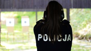 Policjantka stoi tyłem, w tle tarcze do strzelania.